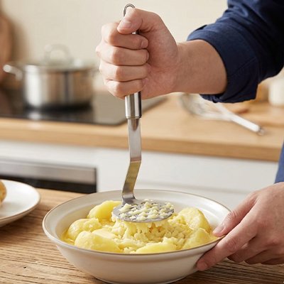 Presse purée cuisinier en chemise bleu comptoir en bois